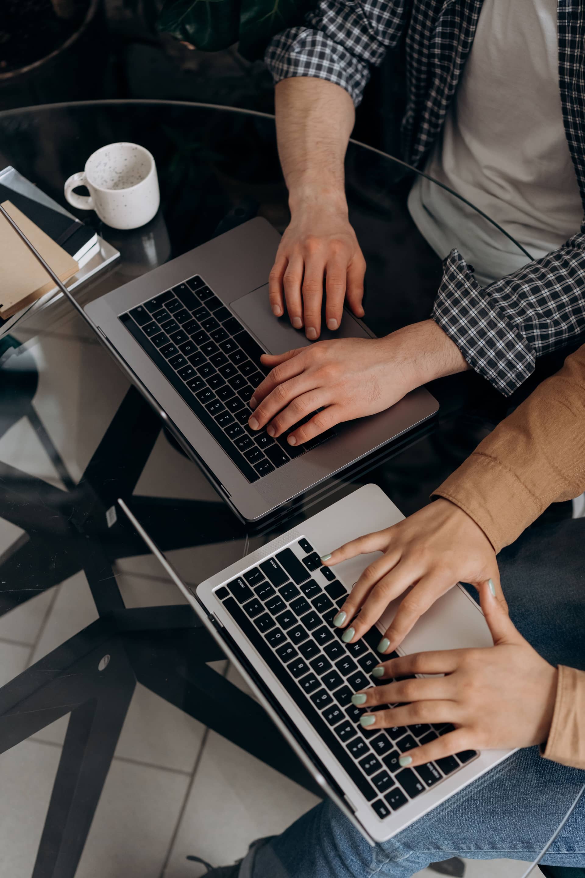 Two people working side by side on laptops